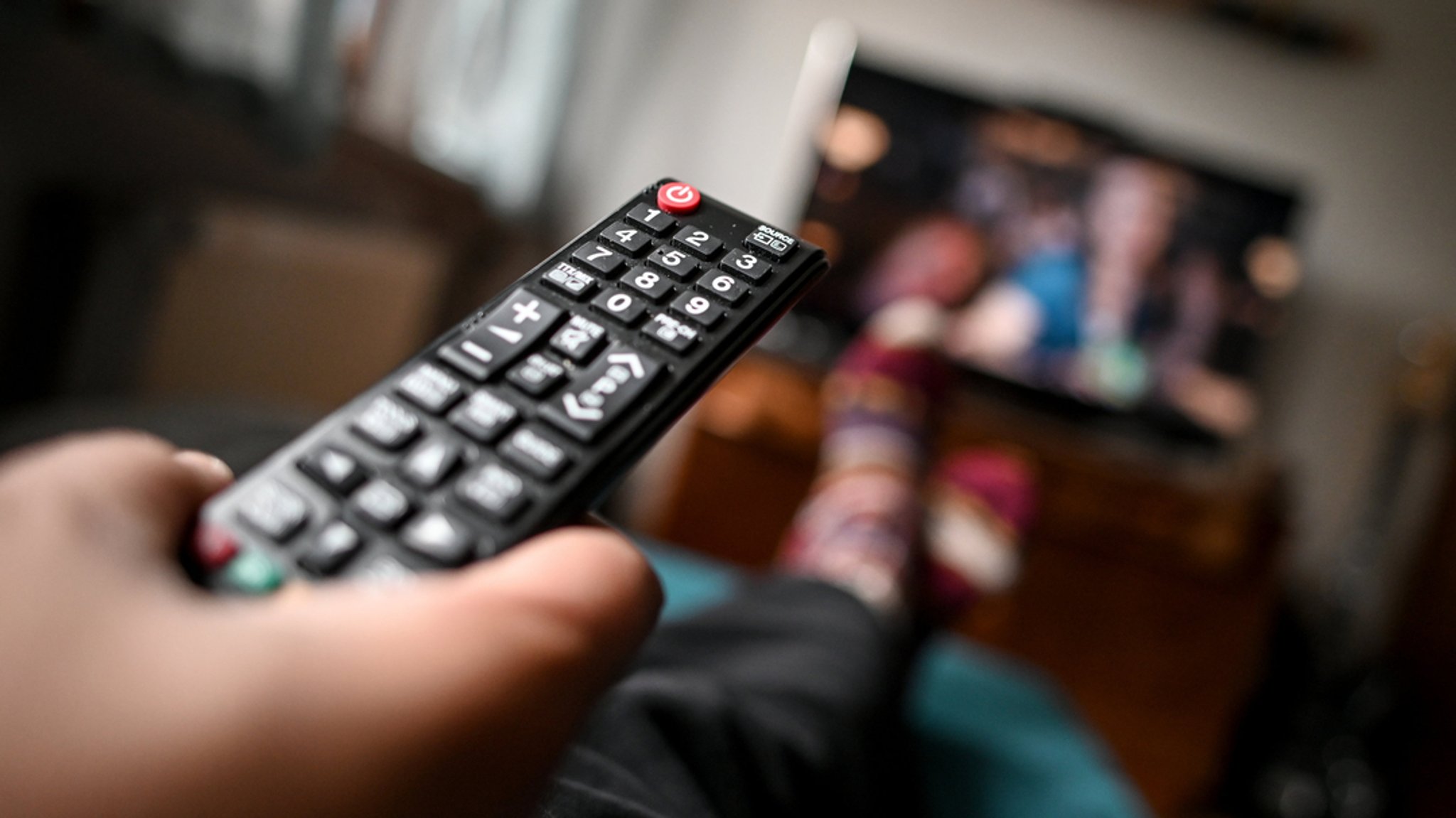 Ein junger Mann sitzt mit einer Fernbedienung vor dem Fernseher. | Bild: dpa-Bildfunk/Britta Pedersen Ein junger Mann sitzt mit einer Fernbedienung vor dem Fernseher.